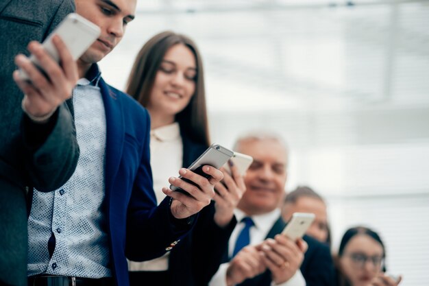 close up group smiling business people looking their smartphone screens 160672 2450